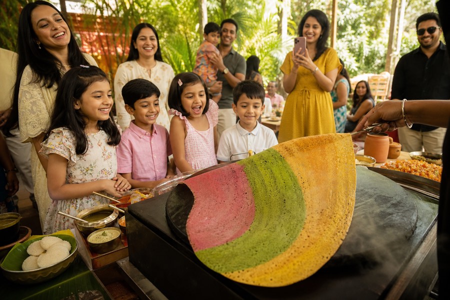 Children watching a brightly coloured dosa being cooked at a party